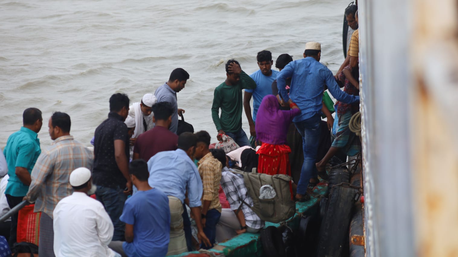 লাল বোট থেকে জাহাজে উঠছে যাত্রীরা।